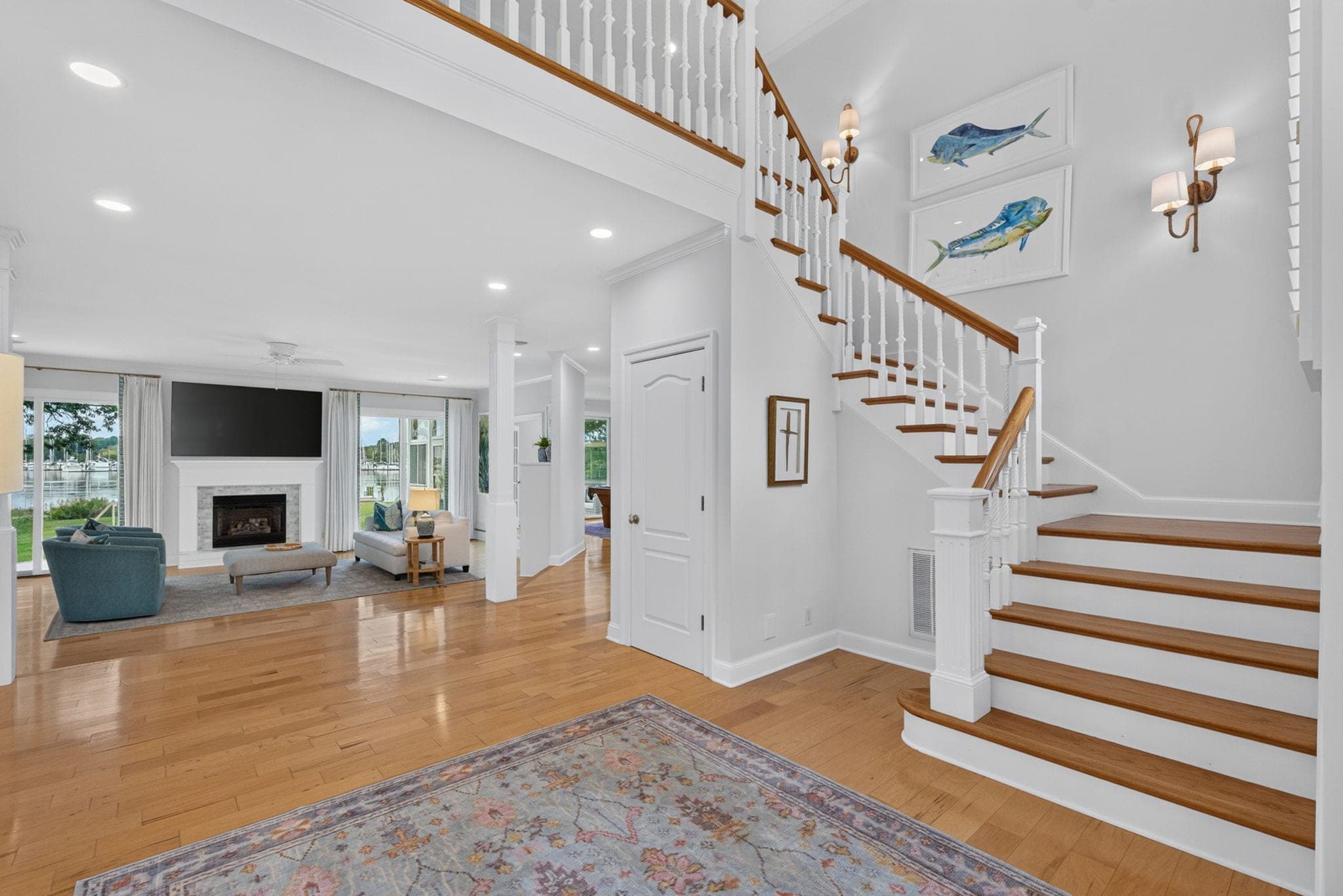 The foyer opens to a curved stair and straight through to the living room and the water beyond.