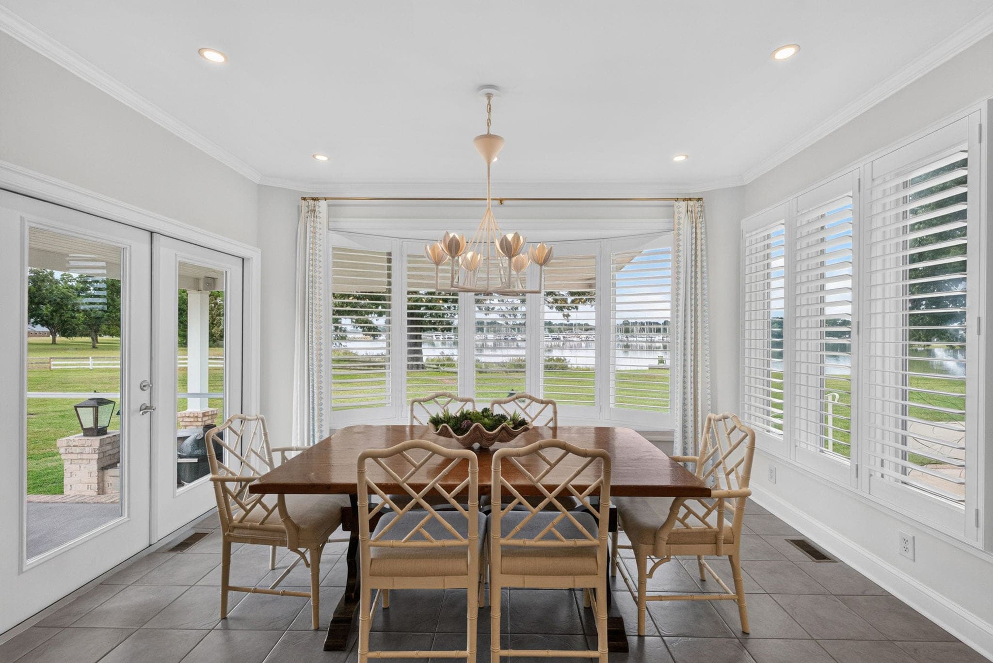 The dining room's bay of plantation-shuttered windows looks out to the lawn and the marina.