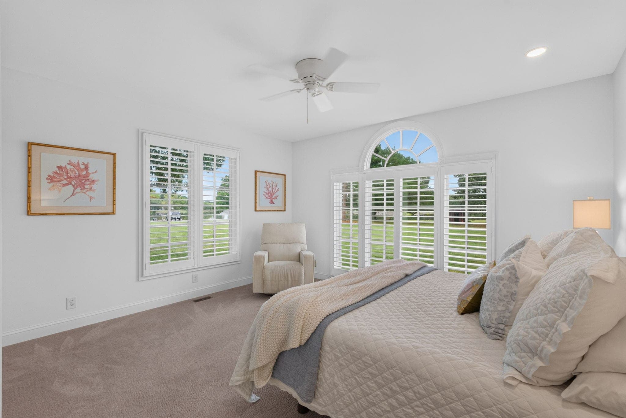 The main-level primary suite, with an arched window to the lawn and its own bath.