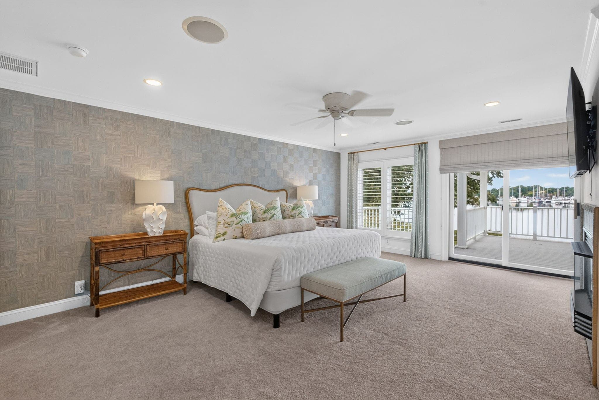 The upstairs primary suite opens to the covered balcony over the water.